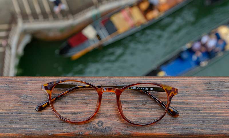 briller som ligger på en bro med båter under